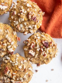 Top down close up image of healthy Morning Glory Muffins sitting on a white backdrop with a red napkin to the side.