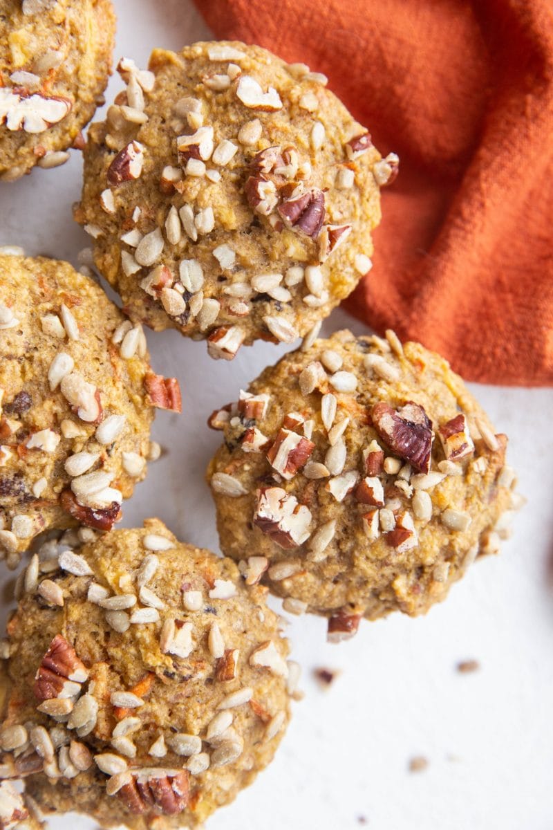 Top down close up image of healthy Morning Glory Muffins sitting on a white backdrop with a red napkin to the side.