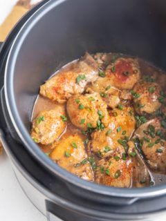Instant Pot full of chicken thighs and sauce, sprinkled with green onion