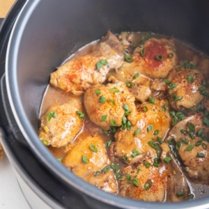 Instant Pot full of chicken thighs and sauce, sprinkled with green onion