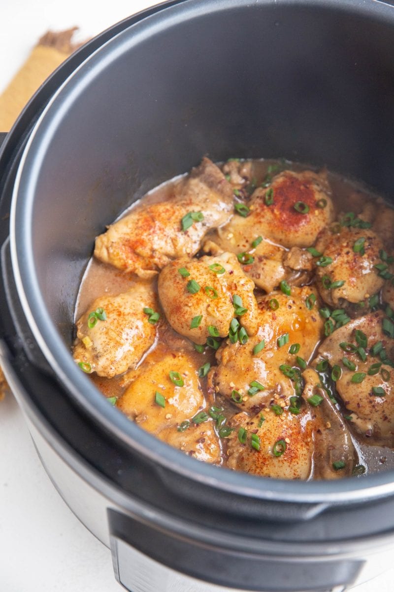 Instant Pot full of chicken thighs and sauce, sprinkled with green onion