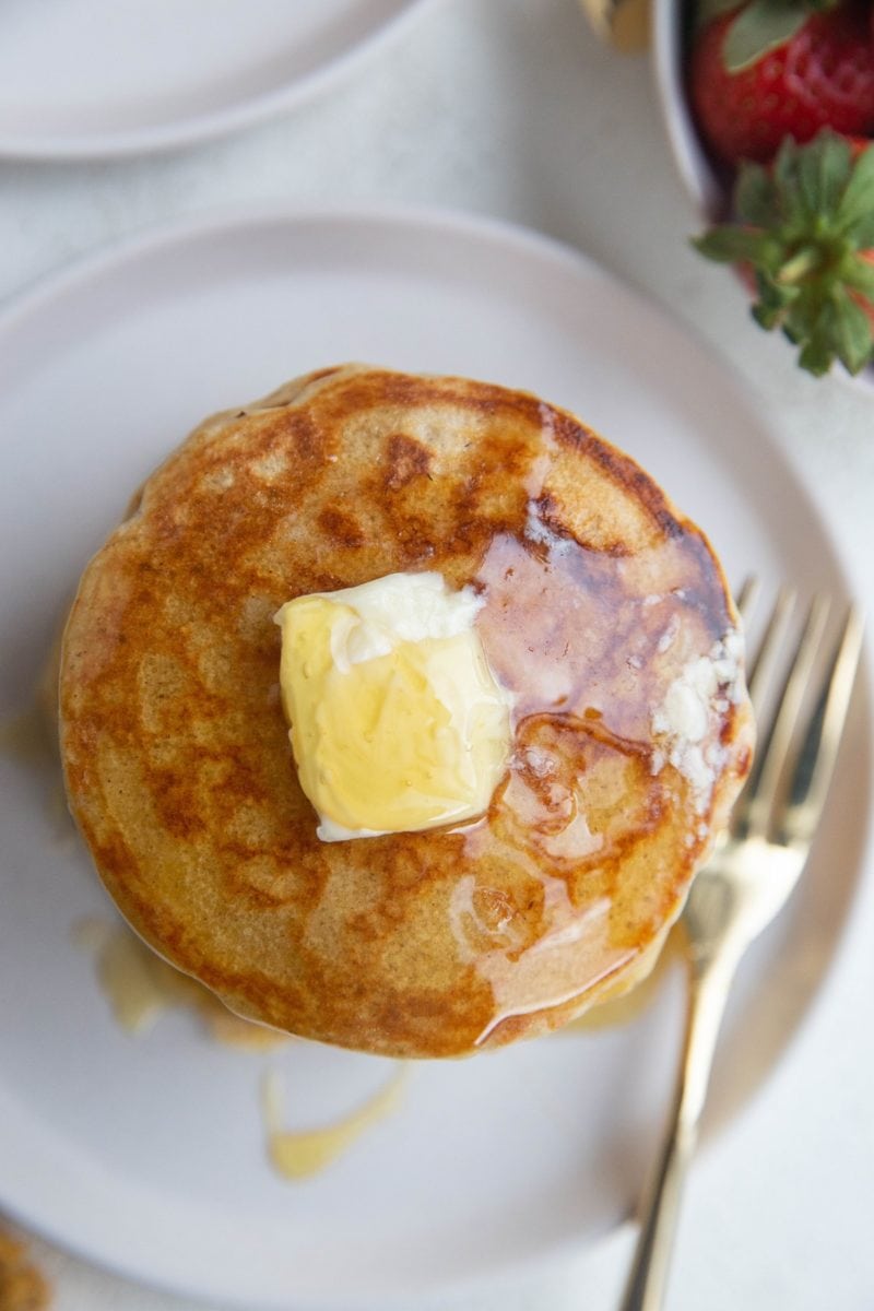Top down view of a stack of pancakes with butter and honey on top.