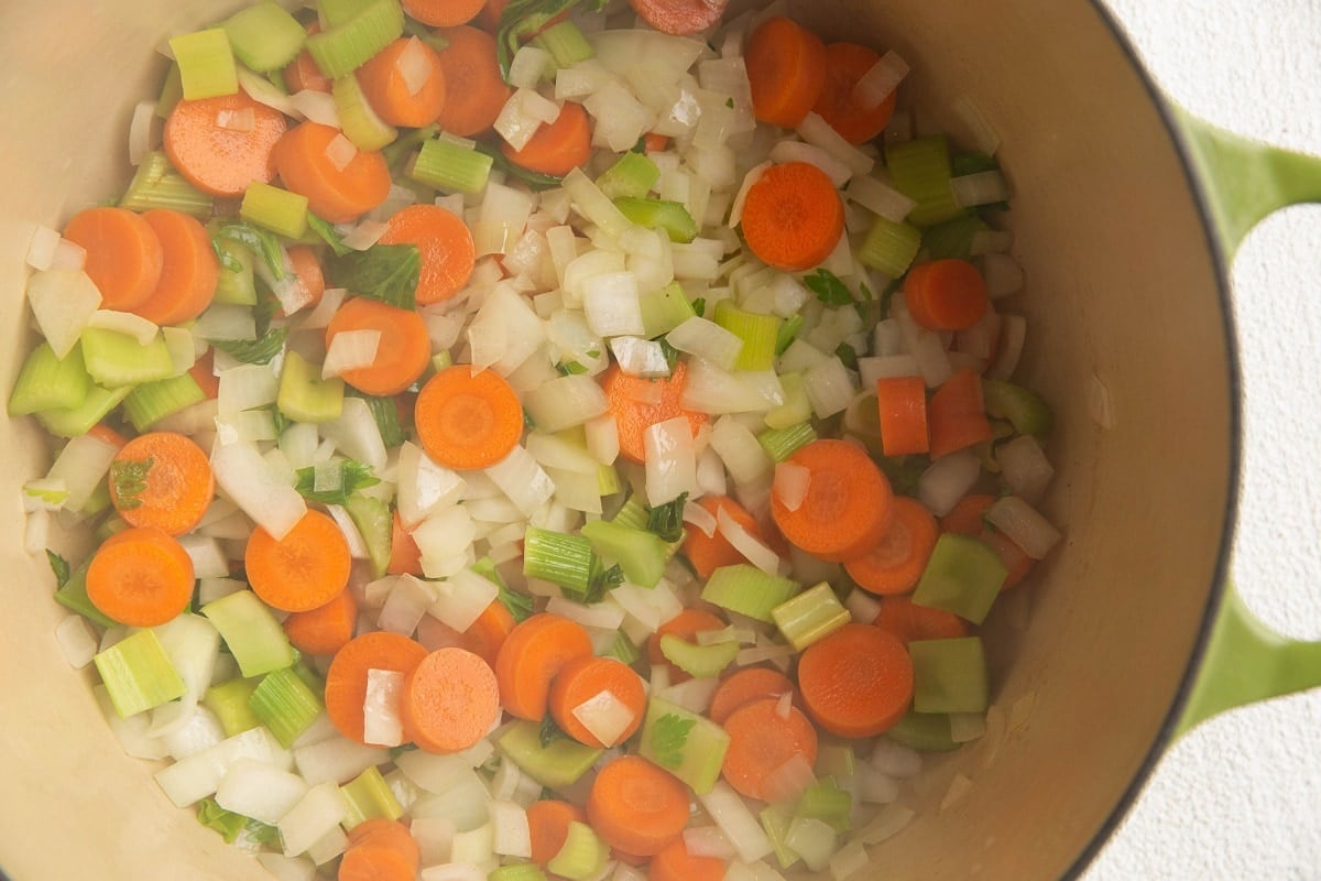 Onions, carrots, and celery sautéing in a large soup pot.