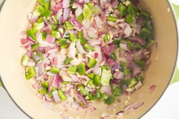 Green bell pepper, garlic and onion sauteing in a pot.