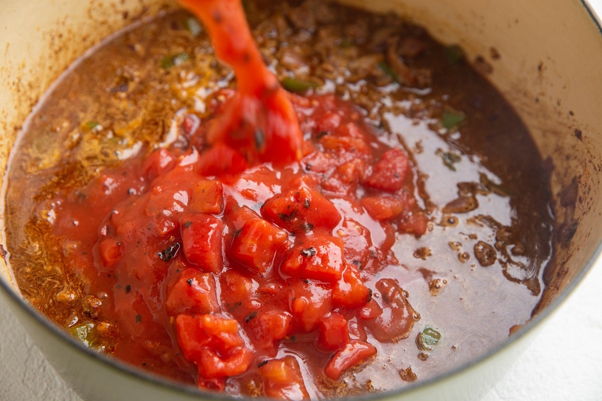 Pouring in the diced tomatoes and broth.