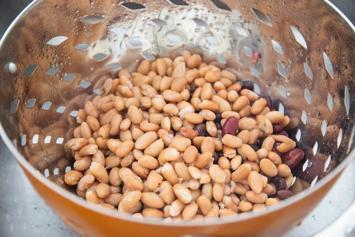 Three cans of beans draining in a colander.