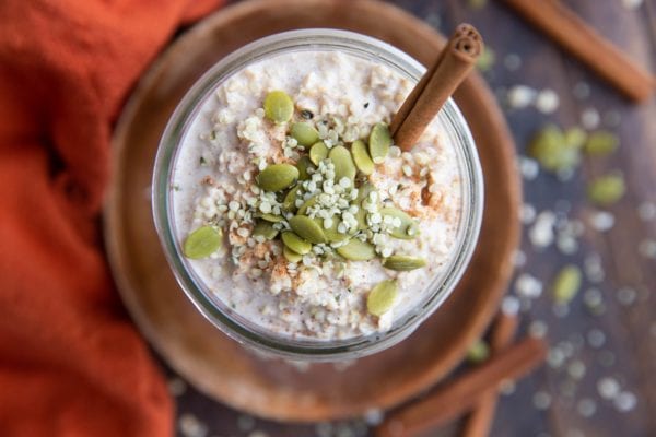 Horizontal photo of a jar full of overnight oatmeal with pumpkin seeds and hemp seeds on top.