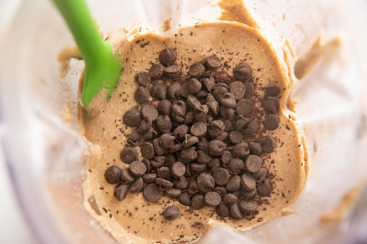 Banana bread batter in a blender with chocolate chips being stirred in.