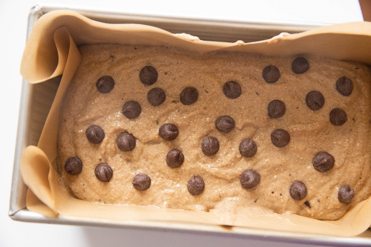 Banana bread batter in a loaf pan with chocolate chips sprinkled on top, ready to go into the oven.