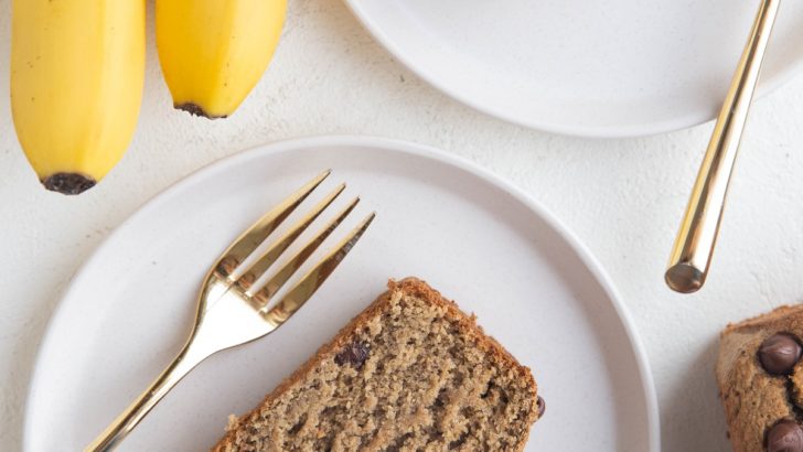 Top down photo of two white plates of slices of banana bread with golden forks, ready to eat.
