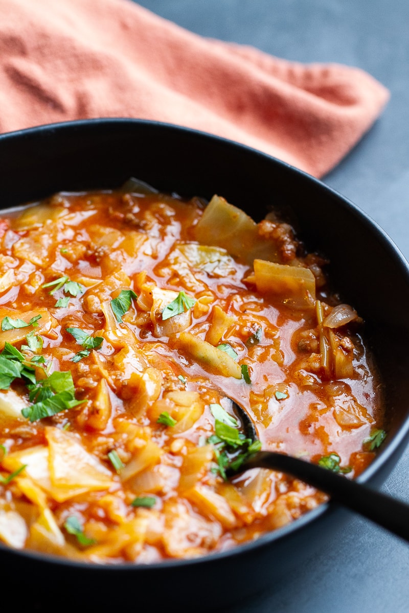 Cabbage Roll Soup in a black bowl with a spoon and a napkin