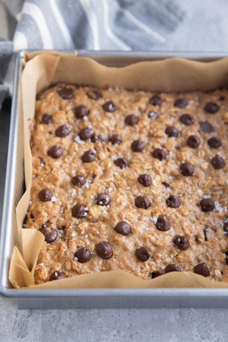 Square baking pan with almond butter cookie bars inside and a striped napkin in the background.