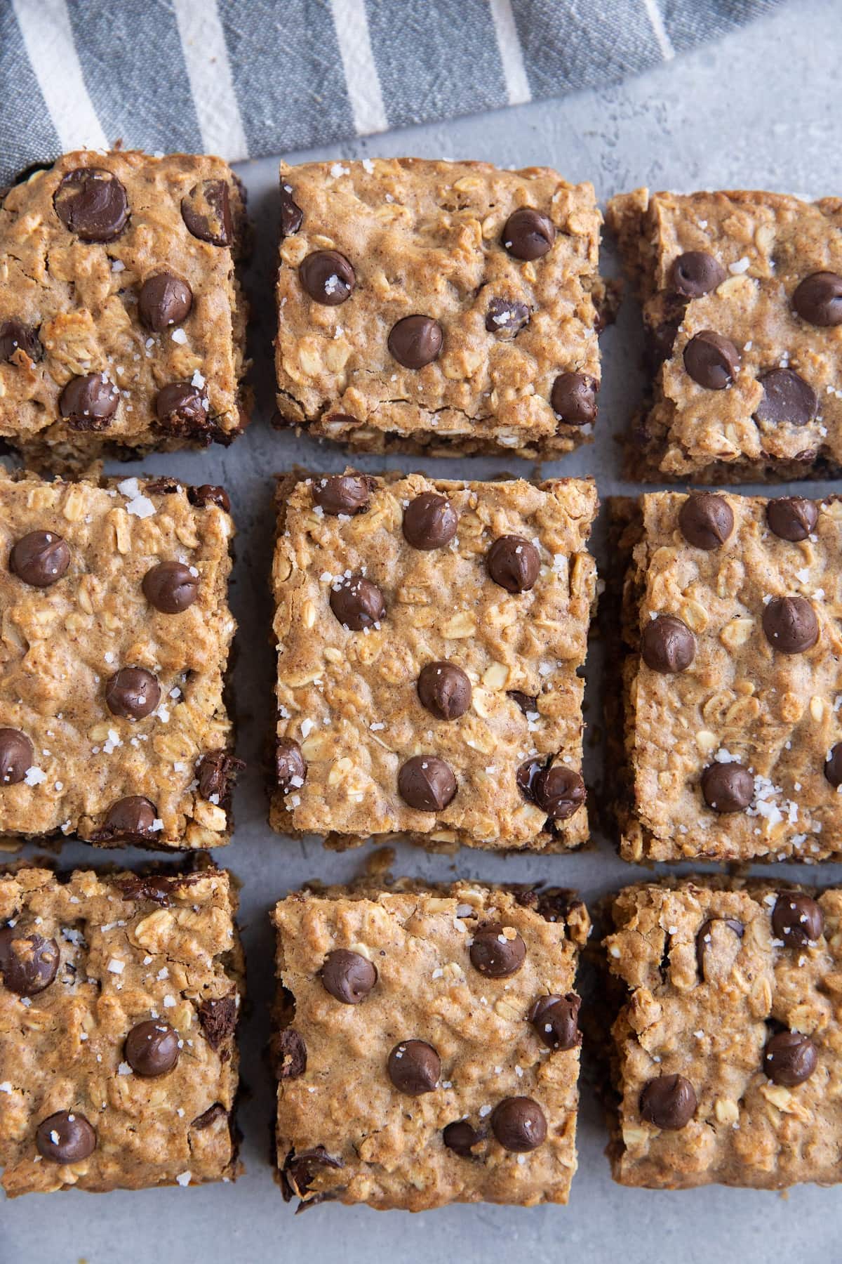 Cookie bars on a grey background with a striped napkin.