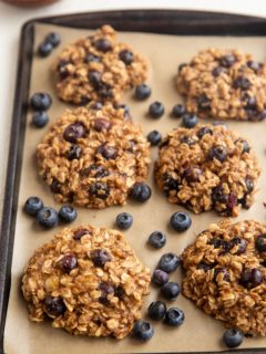 Blueberry Oatmeal Cookies on a baking sheet with fresh blueberries scattered around.