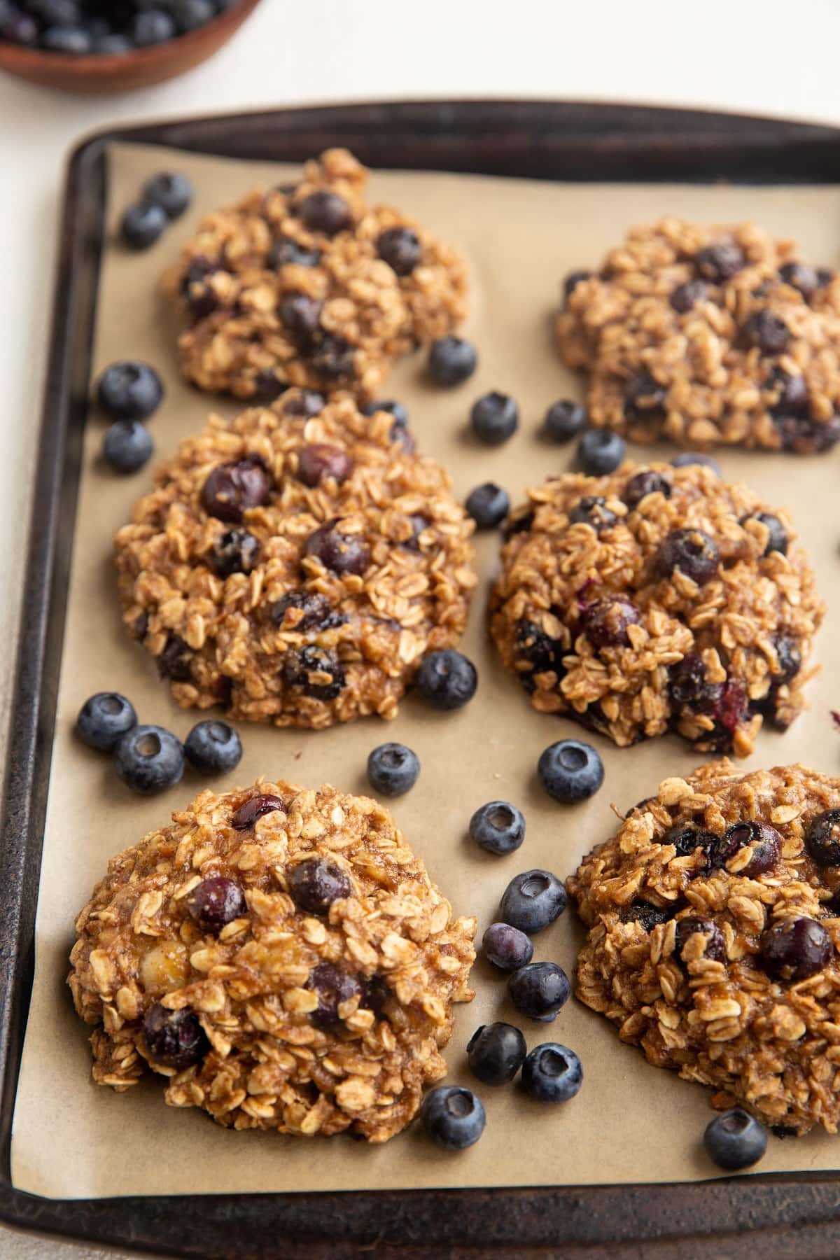 Blueberry Oatmeal Cookies on a baking sheet with fresh blueberries scattered around.