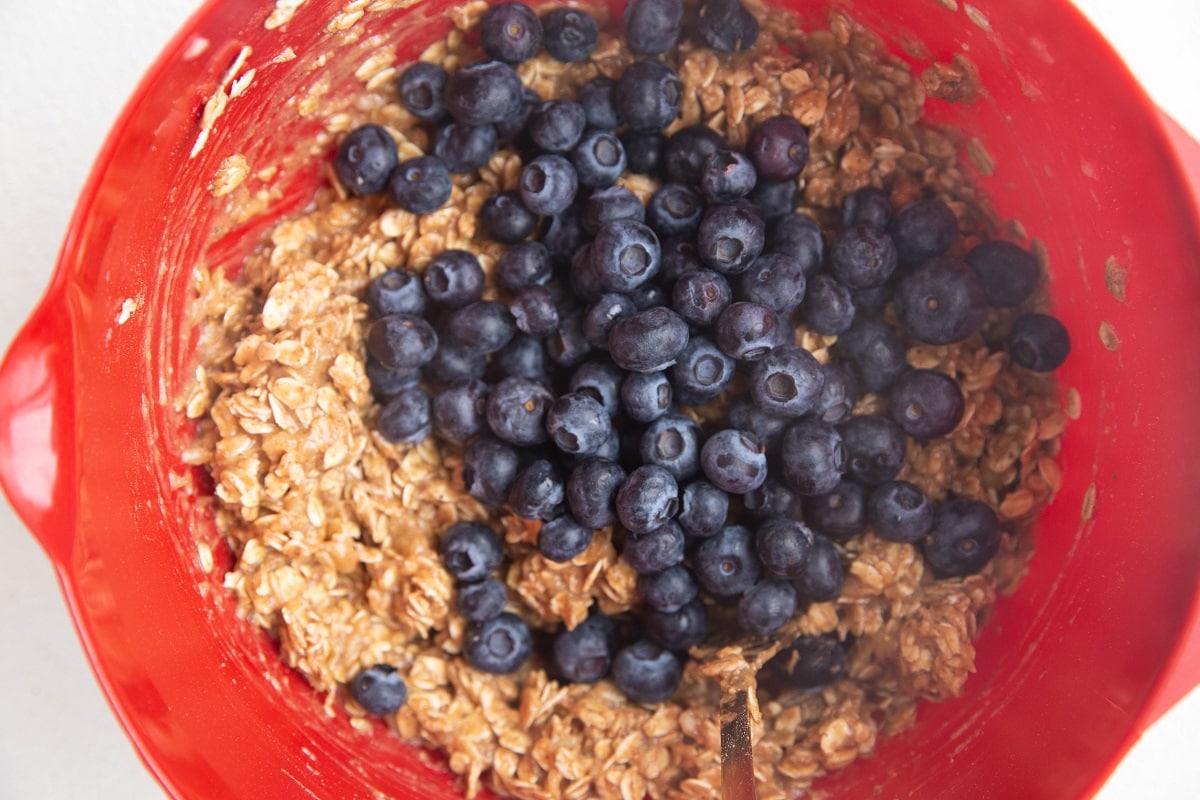 Fresh blueberries on top of oatmeal cookie dough, ready to be mixed in.