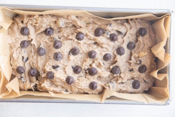 Cassava flour banana bread batter in a loaf pan lined with parchment paper, ready to bake.