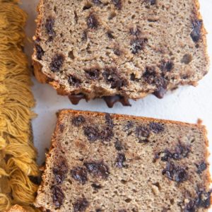 Slices of cassava flour banana bread on white background with a golden napkin to the side.