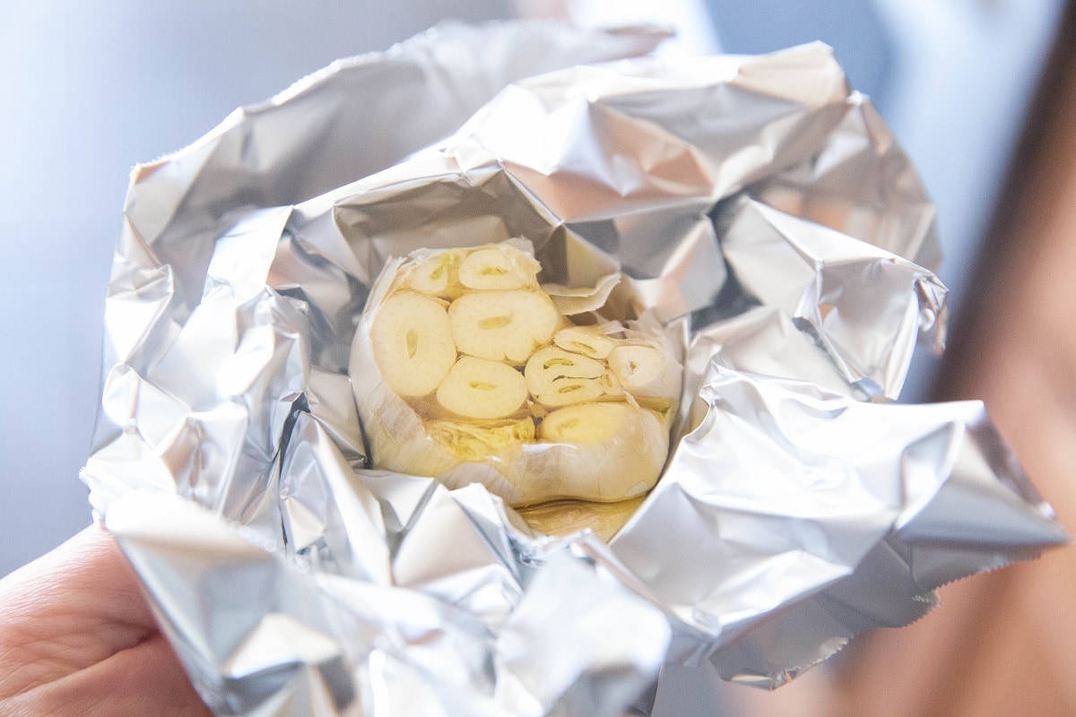 Bulb of garlic drizzled with olive oil, wrapped in foil.