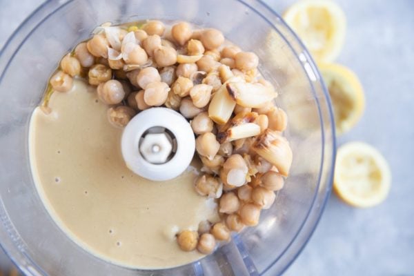 Ingredients for creamy roasted garlic hummus in a food processor.