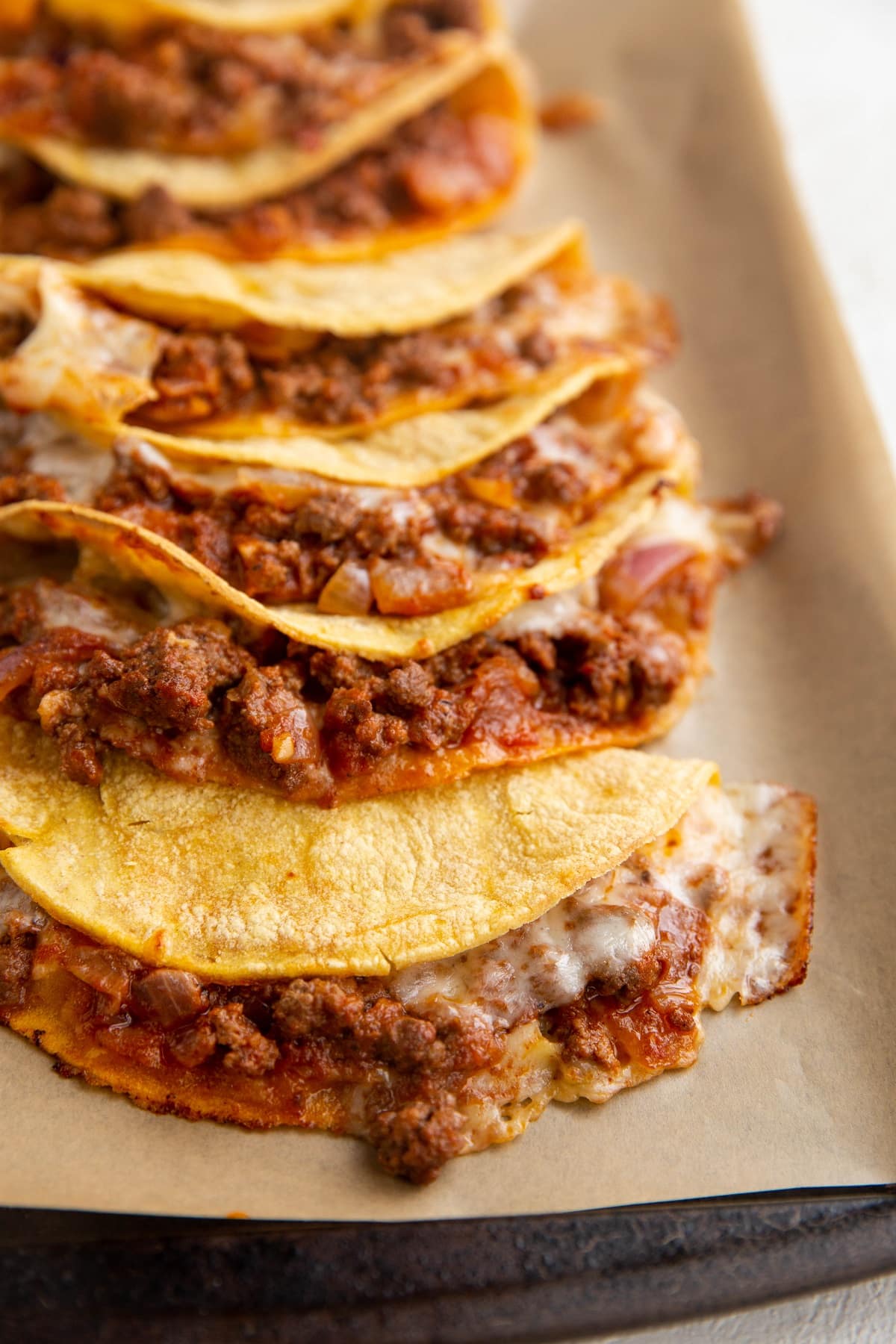 Baking sheet with finished crispy ground beef tacos, ready to eat.