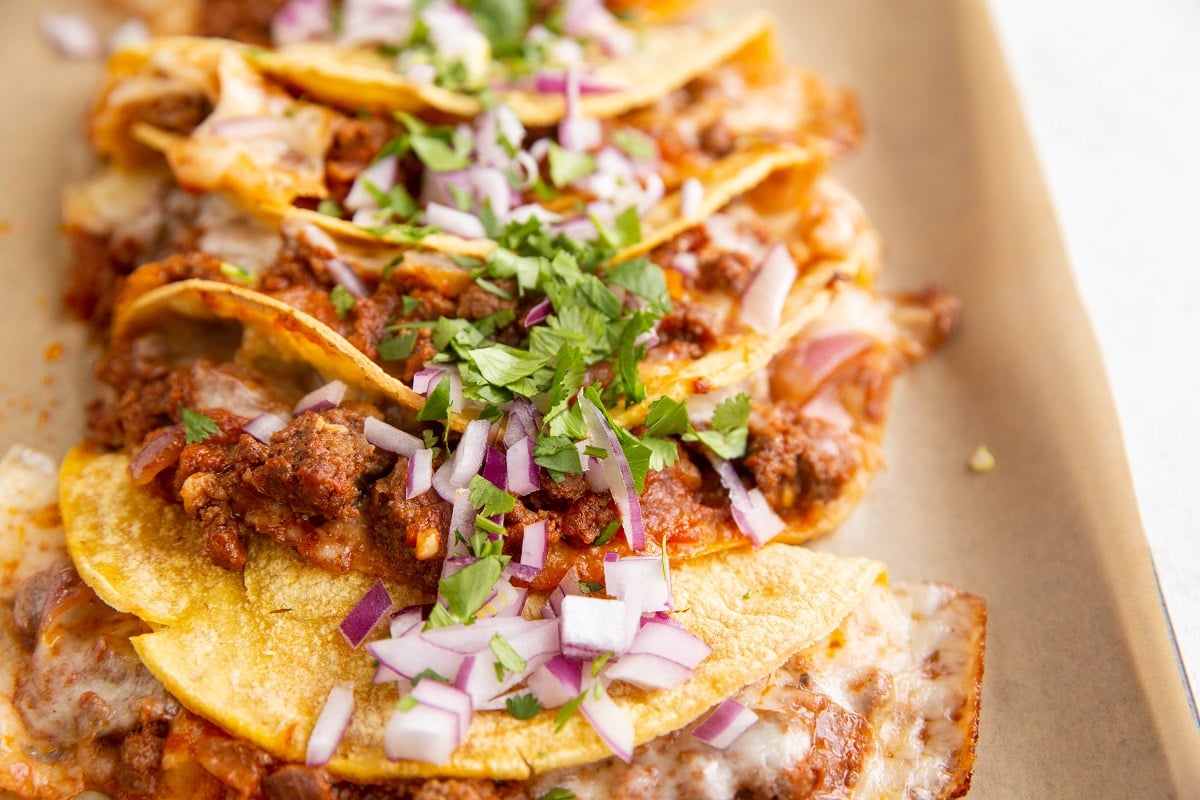 Crispy beef tacos sprinkled with red onions and fresh cilantro.