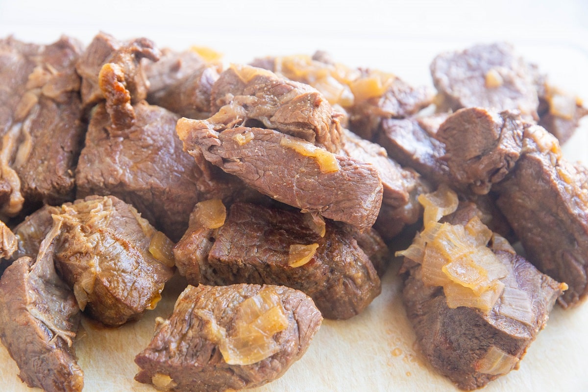 Hunks of cooked beef on a cutting board, ready to be shredded.