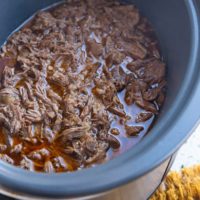 Large crock pot full of shredded beef, ready to be used.