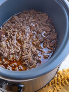 Large crock pot full of shredded beef, ready to be used.