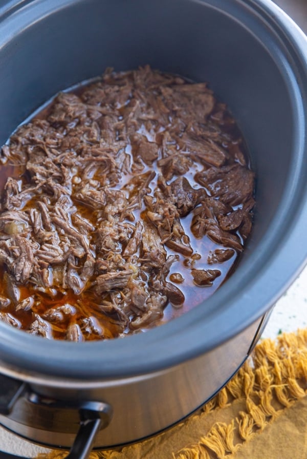 Large crock pot full of shredded beef, ready to be used.