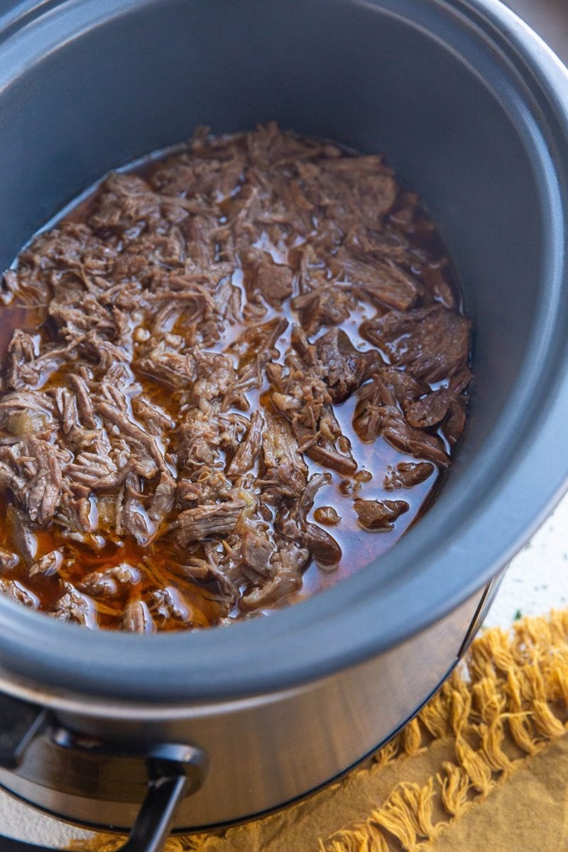 Large crock pot full of shredded beef, ready to be used.