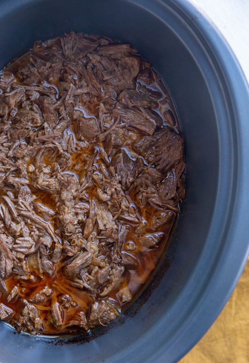 Crock pot full of shredded beef, ready to be used for beef tacos or burritos.