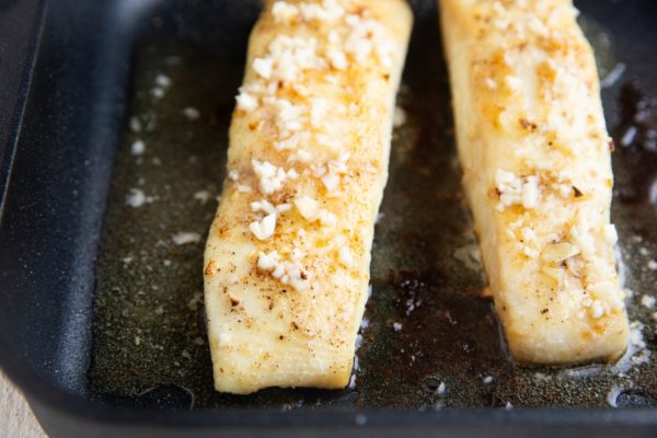 Finished baked halibut in a large baking dish, fresh out of the oven.