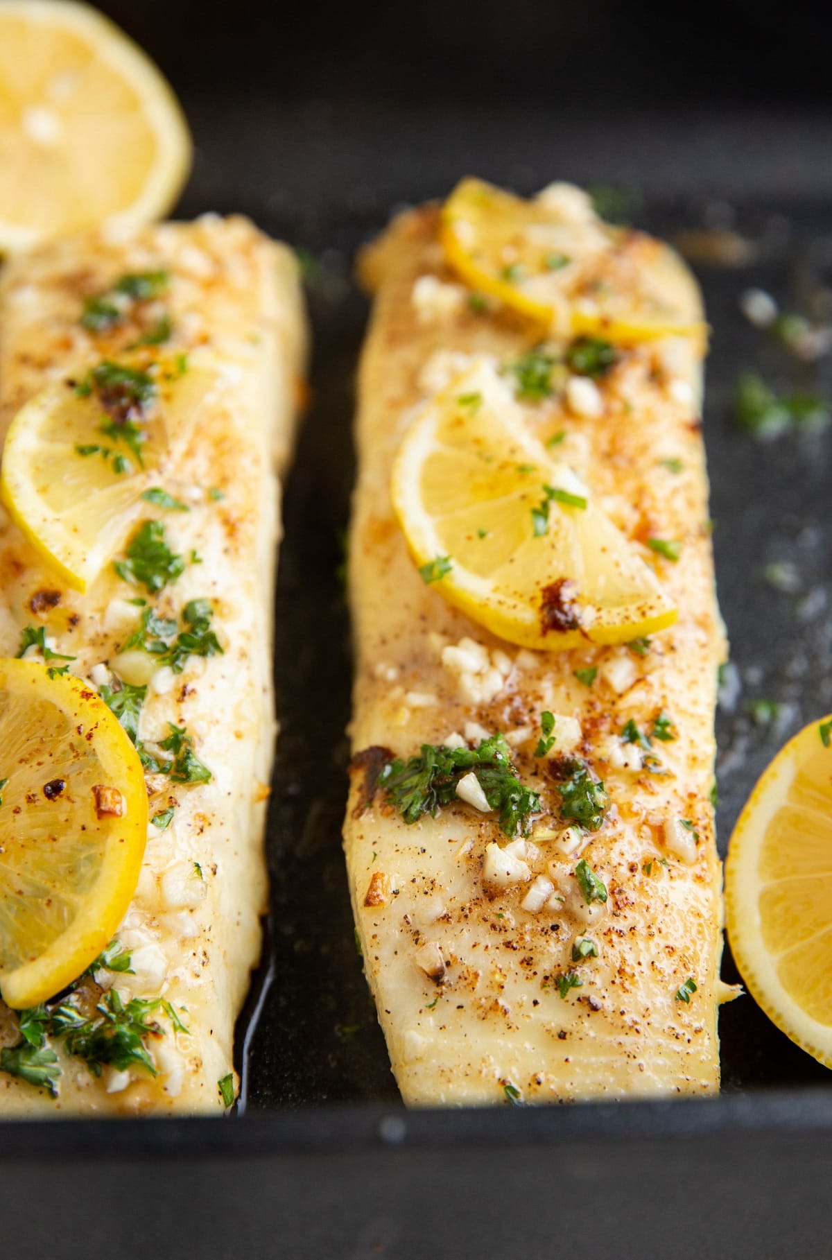 Lemon garlic butter baked halibut fresh out of the oven in a baking dish, ready to serve.