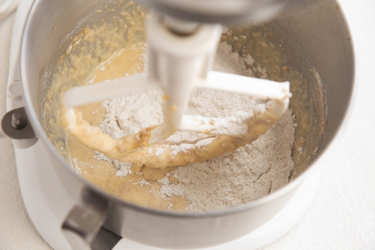 Stand mixer with wet ingredients inside and dry ingredients on top.