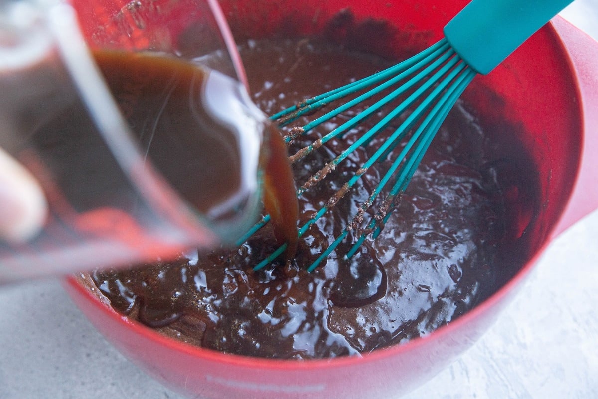 Pouring coffee into cake batter.