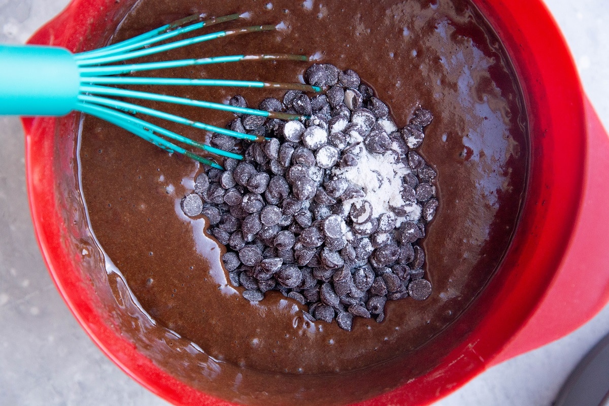 Cake batter in a mixing bowl with chocolate chips on top ready to be mixed in.