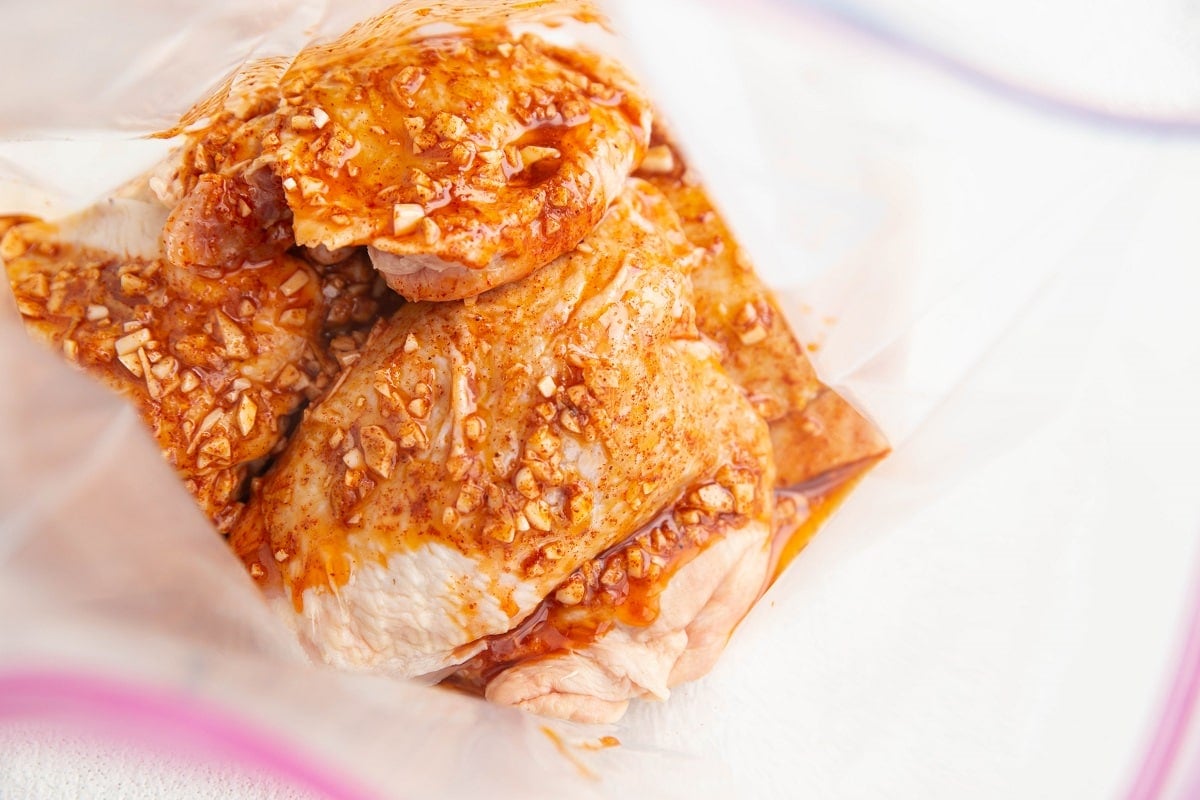 Raw chicken thighs in a zip lock bag with marinade.