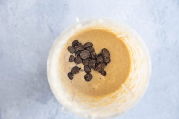 Banana bread mug cake batter in a small blender with chocolate chips sprinkled on top, ready to be mixed into the cake batter.