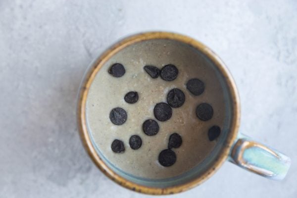 Cake batter in a mug with chocolate chips sprinkled on top, ready to microwave.