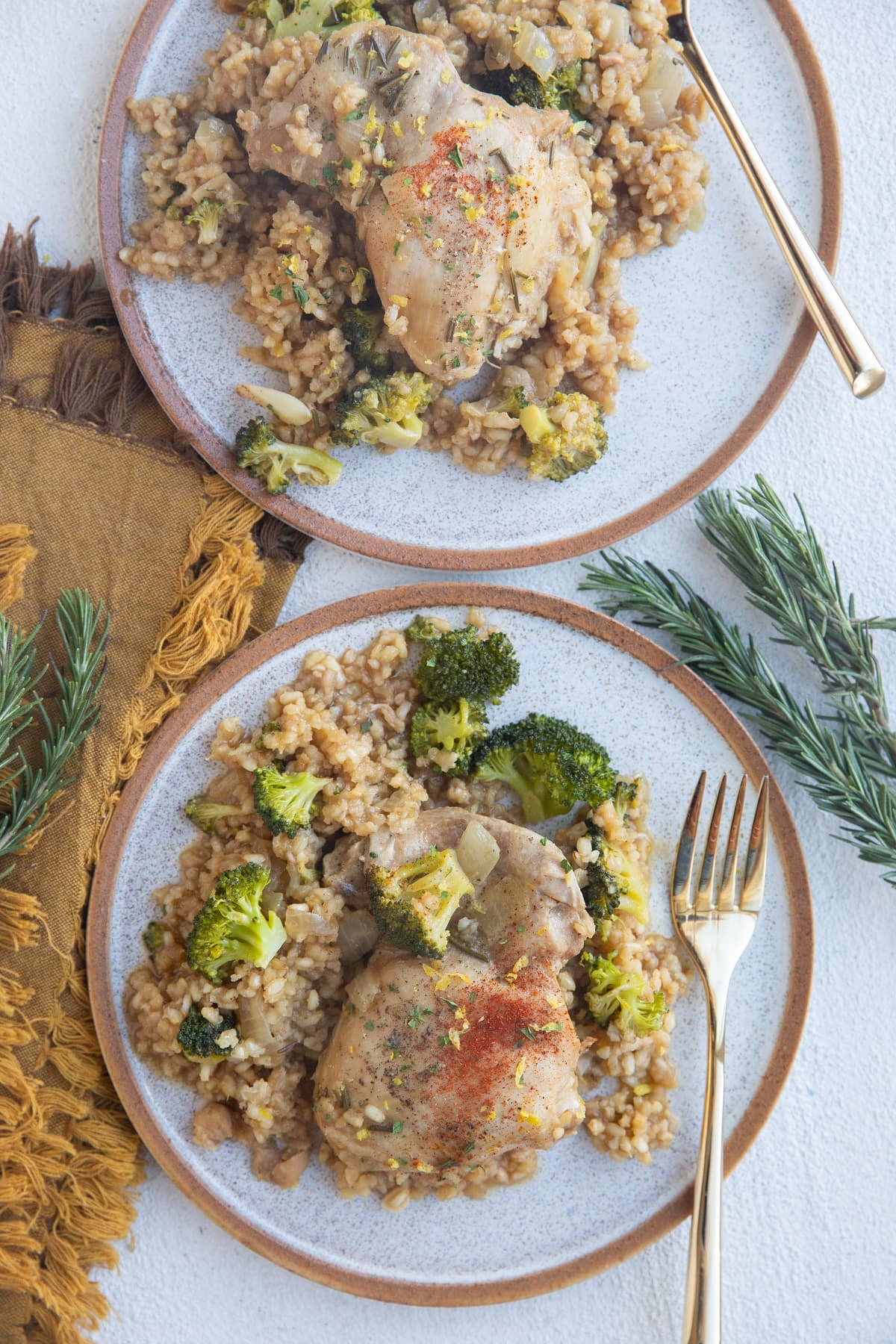 Two plates of chicken and rice with broccoli.