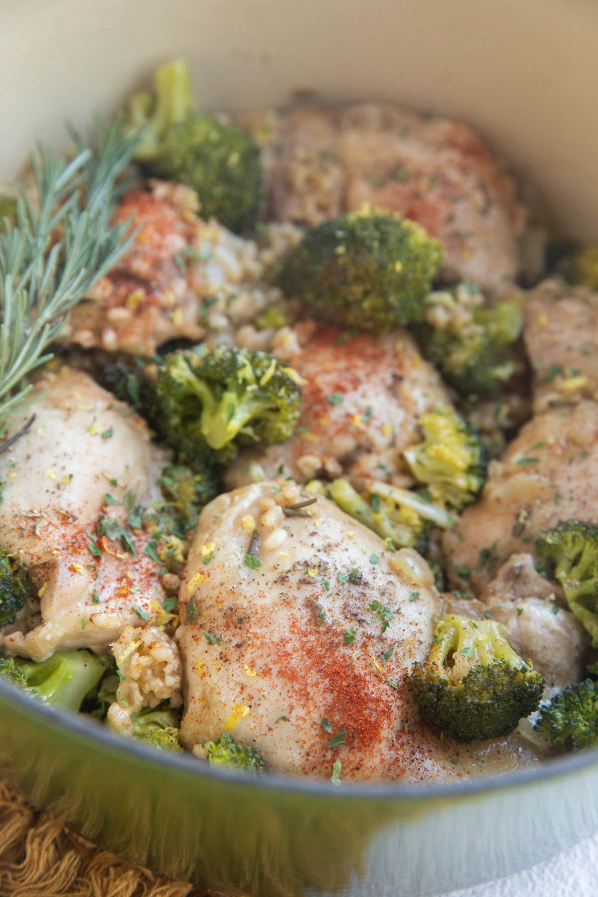 Pot of cooked chicken thighs and brown rice with broccoli and rosemary.