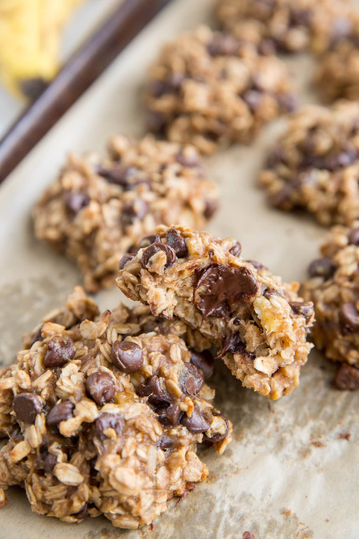 Baking sheet of oatmeal banana cookies with a bite taken out of one of the cookies.