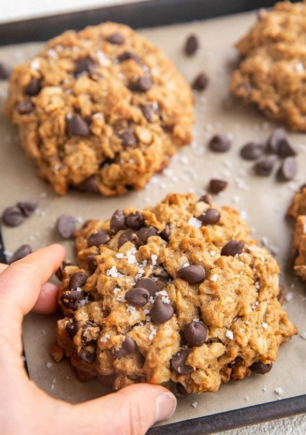 Hand picking up a peanut butter oatmeal chocolate chip cookies.