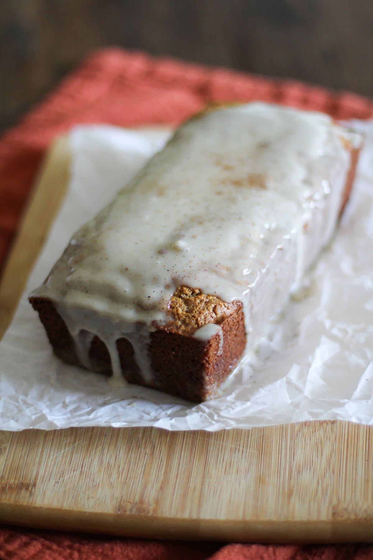 Loaf of eggnog bread on a cutting board with a glaze on top