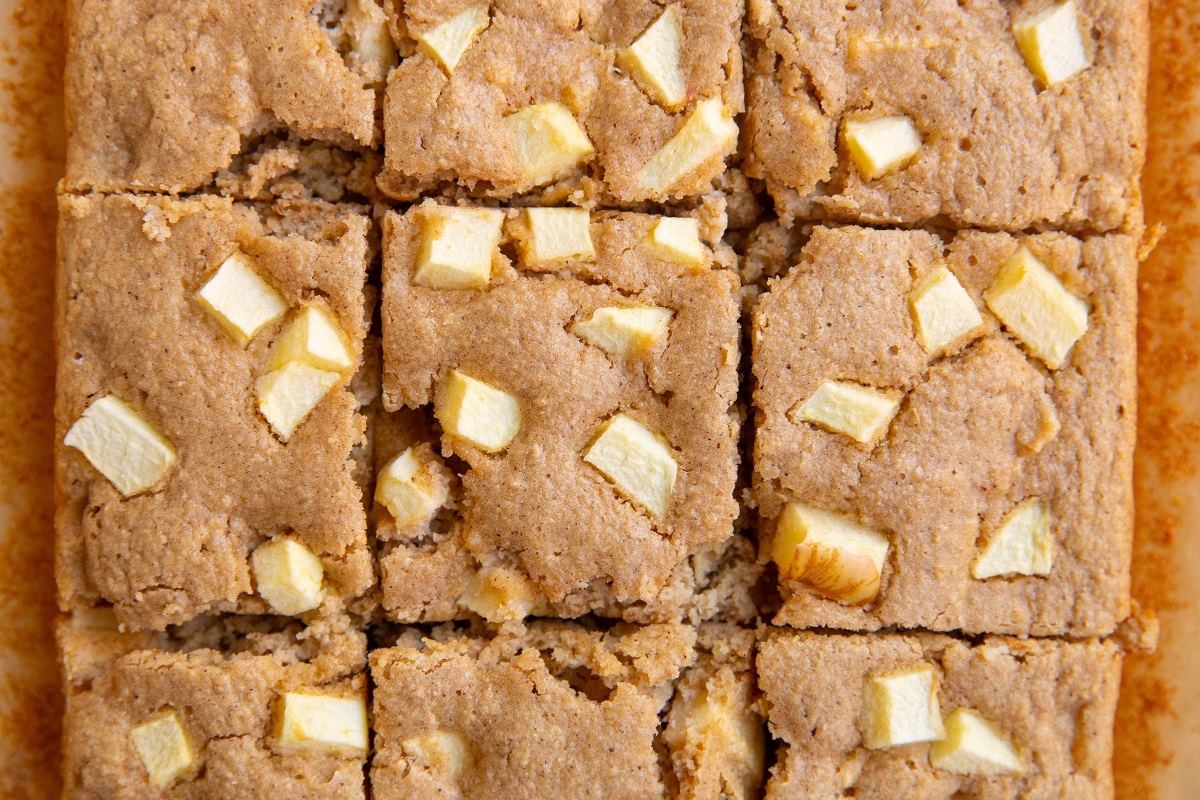 Sliced apple cake on a sheet of parchment paper.