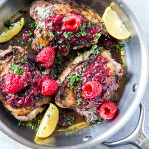 top down photo of balsamic raspberry jam chicken with raspberry jam to the side and sprigs of parsley