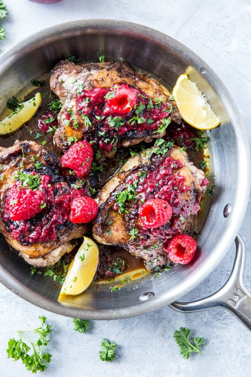 top down photo of balsamic raspberry jam chicken with raspberry jam to the side and sprigs of parsley