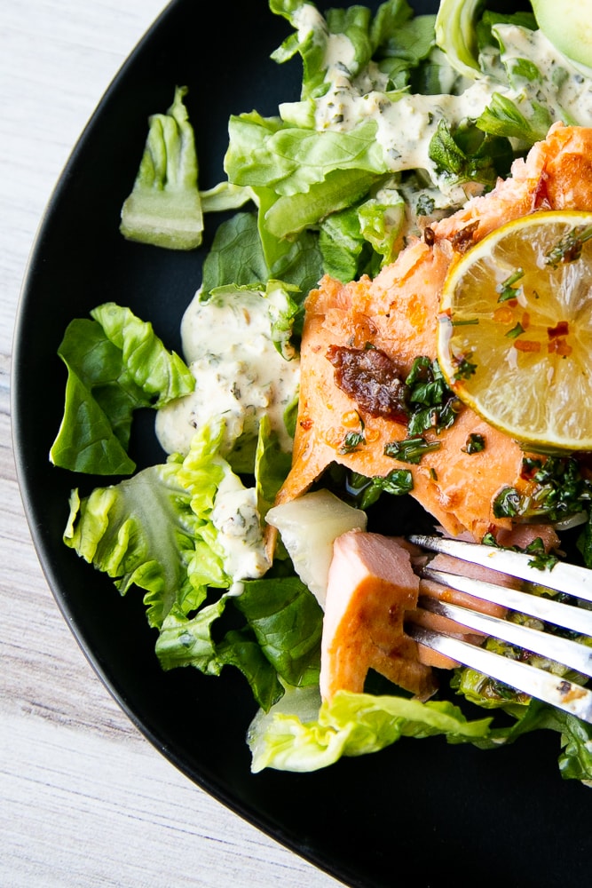 Sweet Chipotle Salmon on a bed of lettuce with dressing.