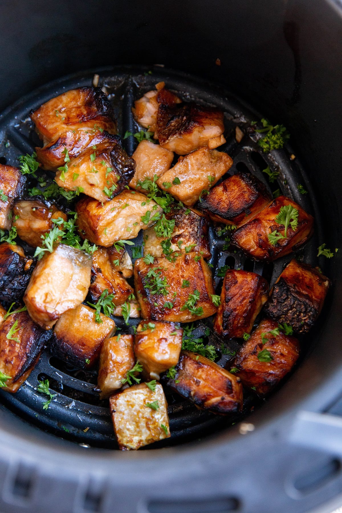 Salmon bites in the basket of an air fryer, ready to serve.